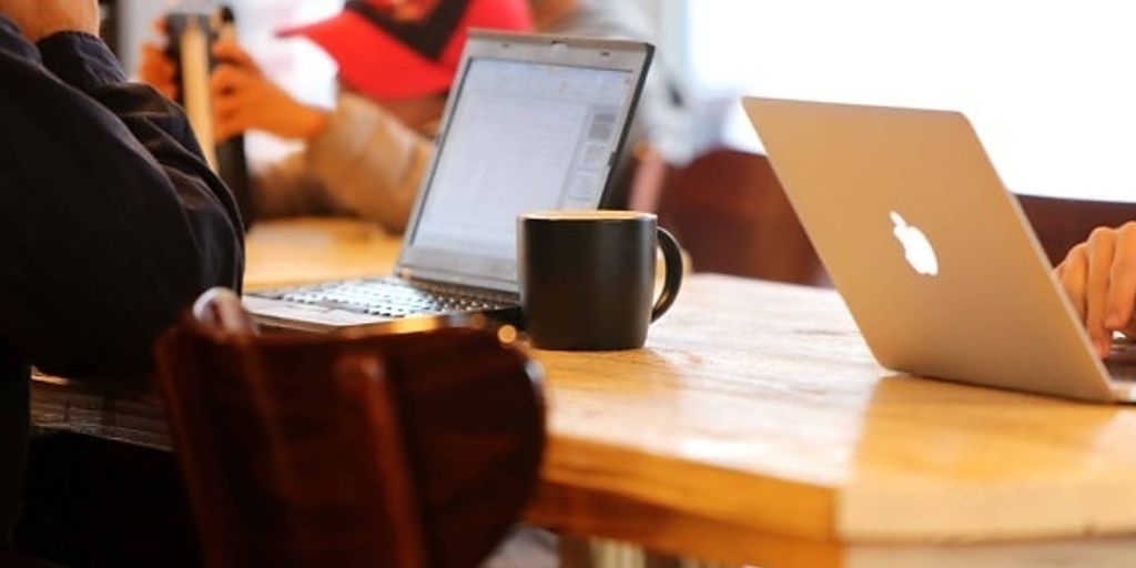 person using laptop in a coffee shop with a VPN icon